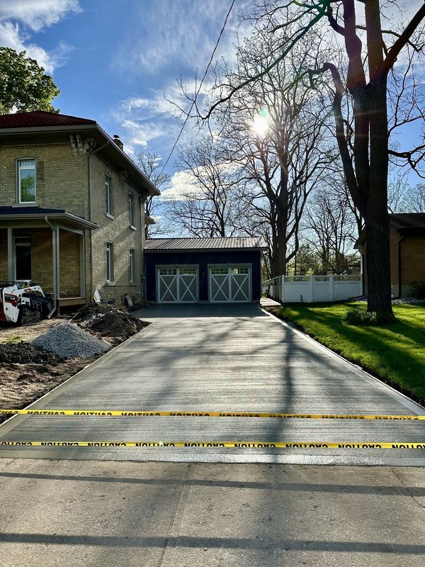 Freshly poured concrete driveway leading to a detached two-door garage.