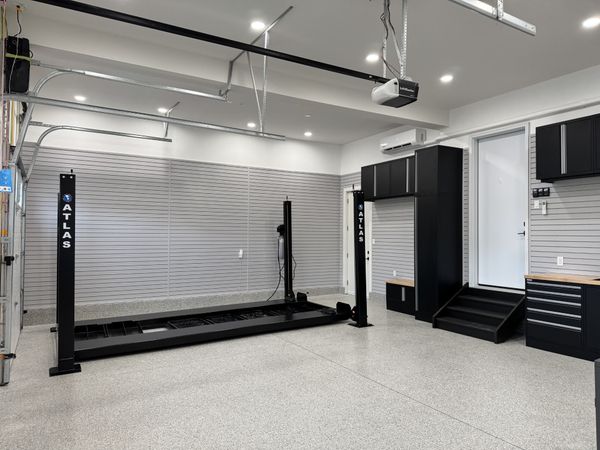Finished garage with wall panels, storage cabinets, lighting and a speckled epoxy floor.
