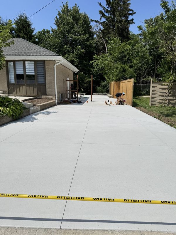 New concrete driveway and walkway beside a brick house.